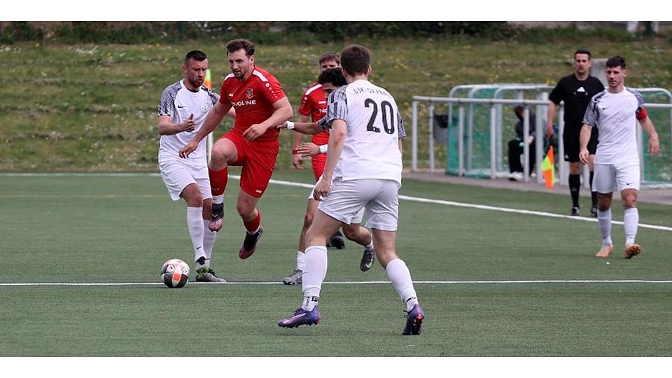 Bingens Kai Wilske (rotes Trikot) geht in dieser Aktion an zwei Schifferstädtern vorbei.	