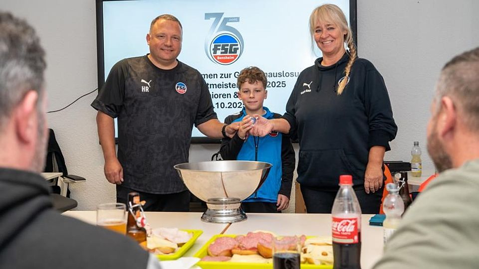 Die Auslosung zu den Bensheimer Hallenfußball-Stadtmeisterschaften Ende Dezember leiteten Holger Rettig (links) und Karin Jäger von Gastgeber FSG, während Luca Schaffert als „Glücksfee“ fungierte. 	Foto: Thomas Neu