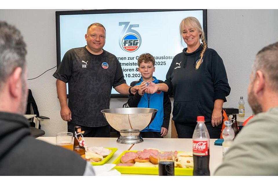 Die Auslosung zu den Bensheimer Hallenfußball-Stadtmeisterschaften Ende Dezember leiteten Holger Rettig (links) und Karin Jäger von Gastgeber FSG, während Luca Schaffert als „Glücksfee“ fungierte. 	Foto: Thomas Neu