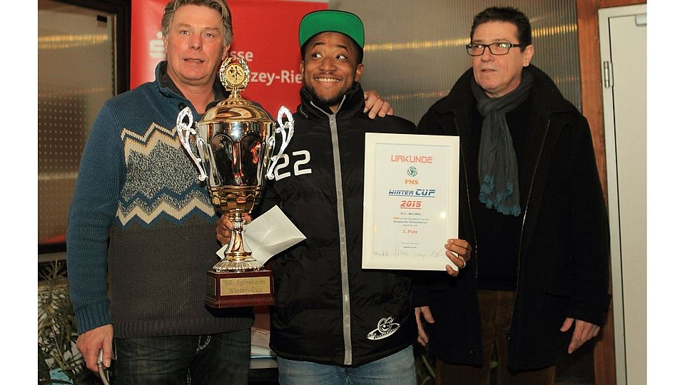 Gequältes Grinsen bei Otmar Müller (links) und grimmiger Blick bei Hans-Philipp Schmitt (rechts). Das geringe öffentliche Interesse am Spiesheimer Wintercup stimmt die Organisatoren nachdenklich. Freude hat nur Bodenheim-Spieler Nelson Kari-Kari (mitte), der Gewinnerpokal, Preisgeld und Urkunde entgegen nehmen darf. Foto: Wolff