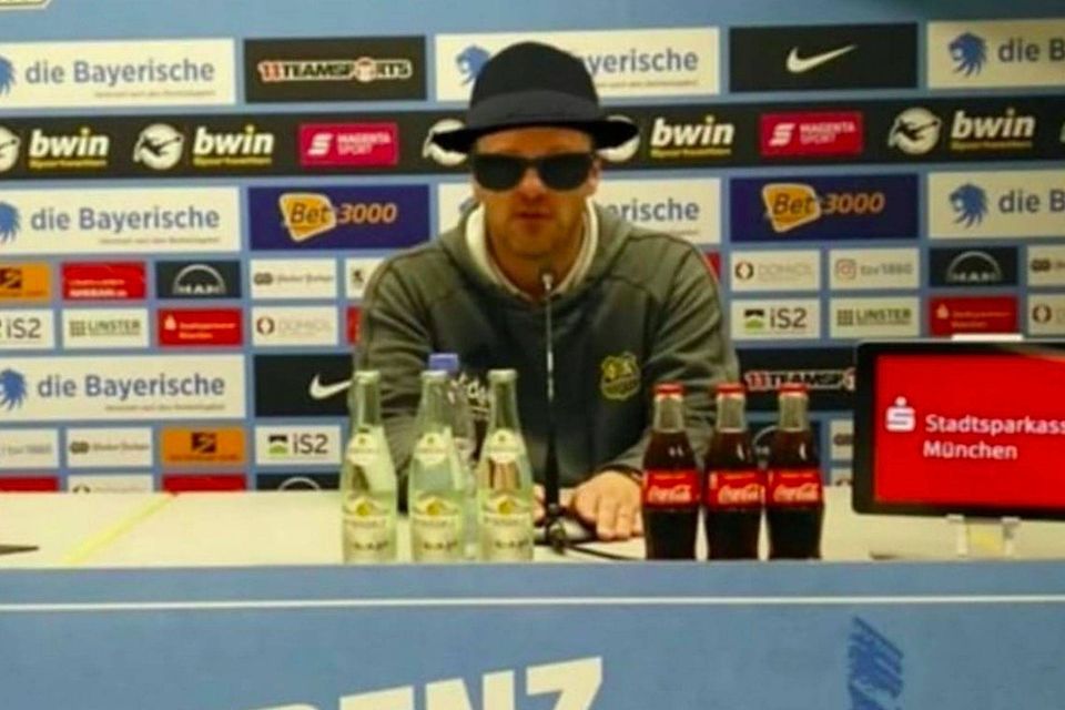Saarbrücken-Coach Lukas Kwasniok mit Sonnenbrille und Hut in der Pressenkonferenz nach dem Spiel gegen den TSV 1860 München.