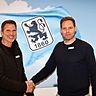 Zwei Männer reichen sich vor dem Wappen des TSV 1860 München die Hand