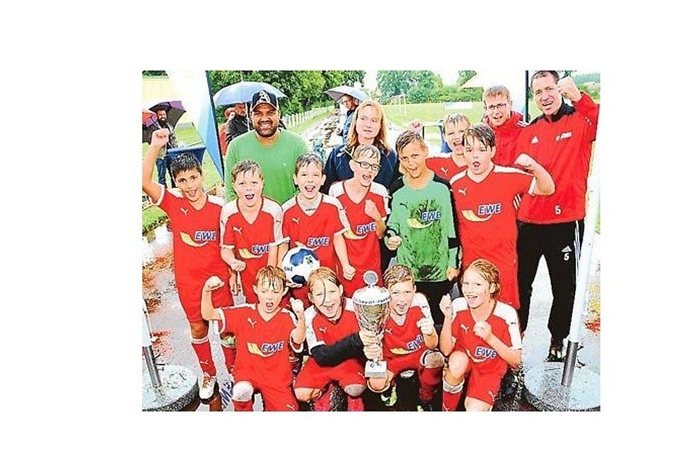 Da ist das Ding: Die  E-Junioren des gastgebenden BV Bockhorn bejubeln den Turniersieg – und der ehemalige Bundesliga-Profi Ailton freut sich mit. Burdenski Events