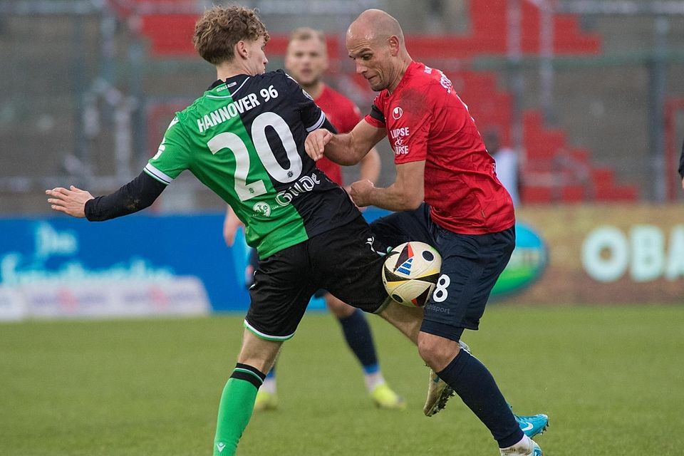 Eingequetschter Ball im Zweikampf zwischen Manuel Stiefler (r.) von der SpVgg Unterhaching und dem Hannoveraner Nick Elias Meier.