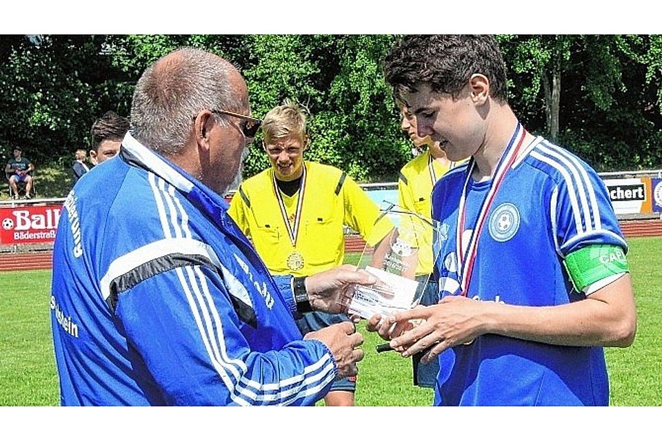 Der Vorsitzende des Kreisfußballverbandes, Klaus Bischof, überreicht Moritz Haye die Pokaltrophäe. Foto: Hartmann (2)