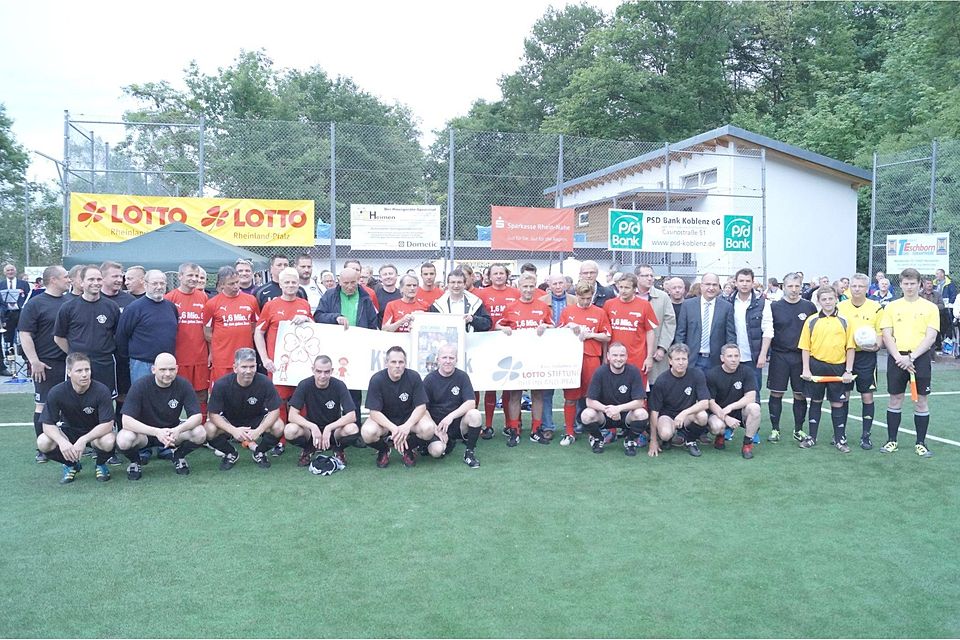 Alle gemeinsam für den guten Zweck: Die Lotto-Elf (Rote Trikots) und die Heimmannschaft des SV Bingerbrück (Schwarz) versammeln sich vor  dem Spiel zum gemeinsamen Erinnerungsfoto. (Bild: Martin Imruck)
