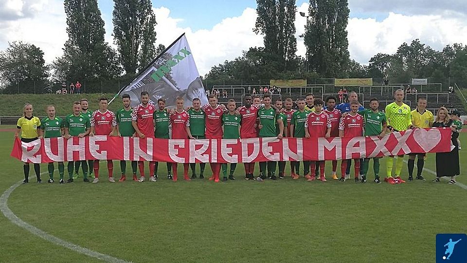 Amateure und Profis stehen zusammen: Vor dem Anpfiff halten die Spieler von Planig und Mainz 05 gemeinsam ein Transparent im Gedenken an Max Keßler hoch.