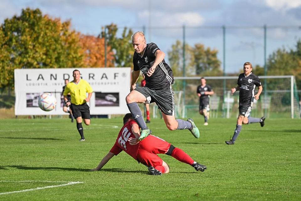 Guldenbachtals-Spielertrainer Lars Flommersfeld, der auch das 1:0 für seine Mannschaft erzielte, ist hier einen Schritt schneller und überspringt den grätschenden Jerrey Renner. 	Foto: Oliver Zimmermann