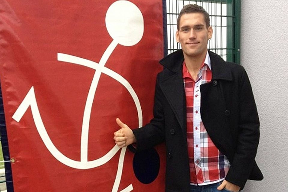 Dominik Gerberich posiert vorm Logo seines neuen Klubs aus Luxemburg. F: UNK