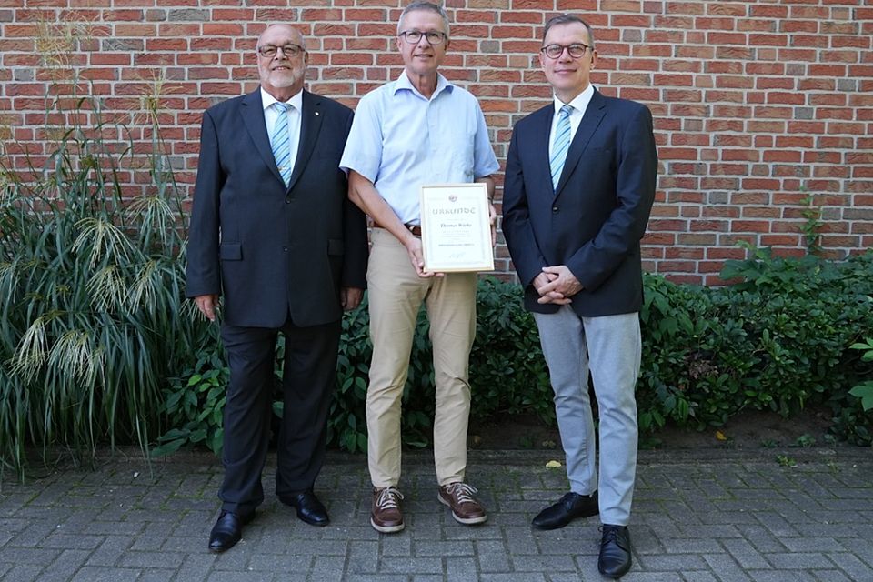 Heiko Wiehn (links) und Christian Röhling (rechts) verliehen Thomas Wiebe die NFV-Verdienstnadel in Gold. 