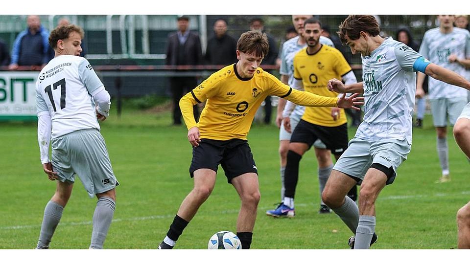 Die SG Sinn/Hörbach gewinnt das A-Liga-Kellerduell gegen die SG Niederoßbach/Wissenbach: Miguel Moncusi (M.) nimmt es hier mit Marcel Häußer (re.) und Elias Reeh von der SG Niederroßbach/Wissenbach auf. © Lorenz Pietzsch