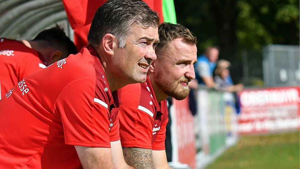 Gedi Sugzda links und Peter Beierkuhnlein rechts sitzen auf der Hallbergmooser Trainerbank und beobachten das Spiel.