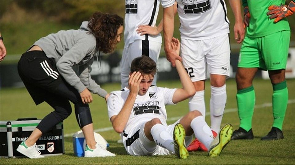 Sinnbildlich für Tegernheims Situation derzeit: Leo Waldhauser von der unterbesetzten Abwehr auf dem (Hosen-)Boden. FC-Physio Samia Farrag kümmert sich um den 23-Jährigen..  Foto: Brüssel