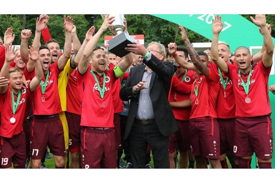 Der Präsident des Westdeutschen Fußballverbandes, Hermann Korfmacher, überreicht Mike Wunderlich den Meisterpokal. Foto: SFB