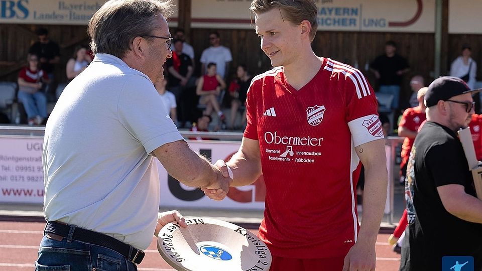 Da ist das Ding - oder besser gesagt die Schale: Herbert Hasak, Kreisspielleiter West, überreicht Landaus Kapitän Simon Weinzierl die Auszeichnung für den Titelgewinn in der Kreisliga Isar-Rott.