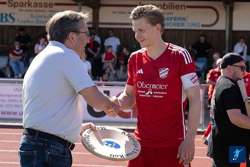 Da ist das Ding - oder besser gesagt die Schale: Herbert Hasak, Kreisspielleiter West, überreicht Landaus Kapitän Simon Weinzierl die Auszeichnung für den Titelgewinn in der Kreisliga Isar-Rott.