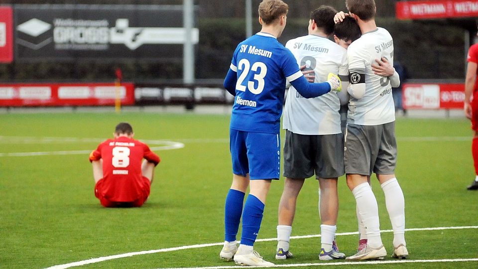 Während die Mesumer Fußballer nach Schlusspfiff ihren 1:0-Sieg feiern, sitzt Peckelohs Erik Mannek (l.) enttäuscht auf dem Boden.