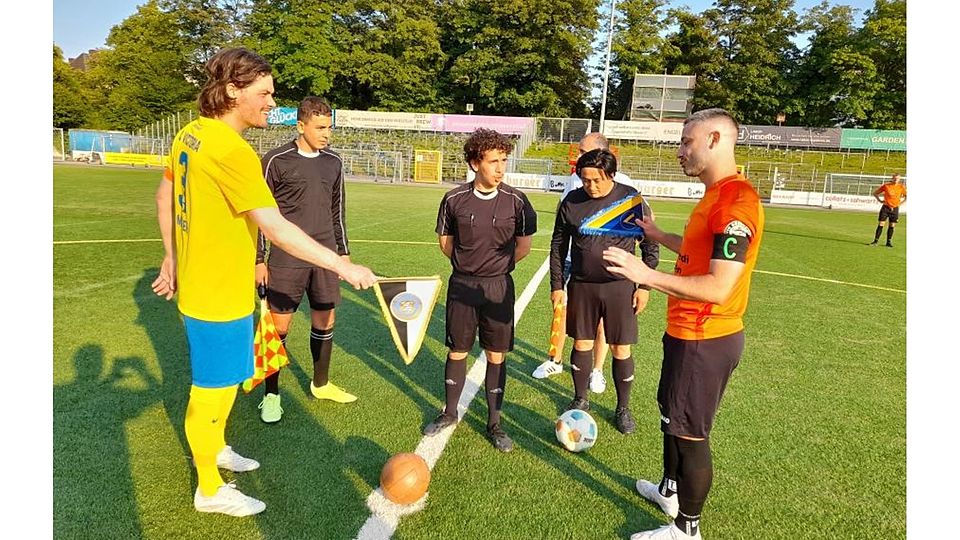 Sönke Meyer (links), der Spielführer des SC Victoria Hamburg und Volkan Celikkan (rechts) Kapitän des VfR Bürstadt tauschen im Traditionsspiel die Wimpel. Die Begegnung steht unter der Leitung von Noah Alabdallah (Victoria Hamburg).	Foto: Matthias Bähr