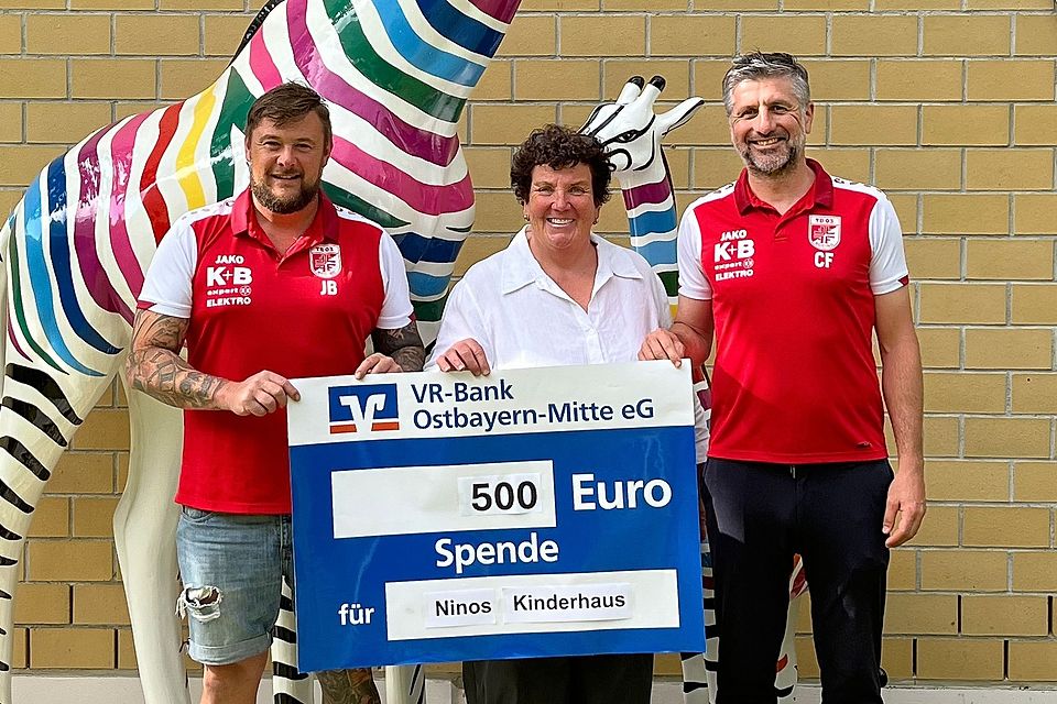 Johannes Bucher (links) und Christian Fleischmann (rechts) von der Fußballabteilung des TB 03 Roding übergeben den symbolischen Spendenscheck an Karin Borchers vom Verein Ninos Freunde e.V.