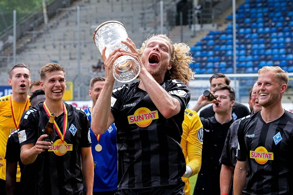 Jesper Pokal stemmt einen Pokal, den er mit Waldhof Mannheim gewonnen hat.