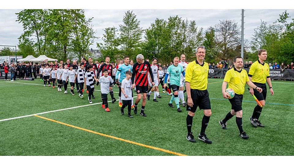 Es geht los: Die Legenden des SC Waldgirmes und die Traditionsmannschaft von Eintracht Frankfurt betreten - angeführt von den Schiedsrichtern - den Rasen. © Jenniver Röczey