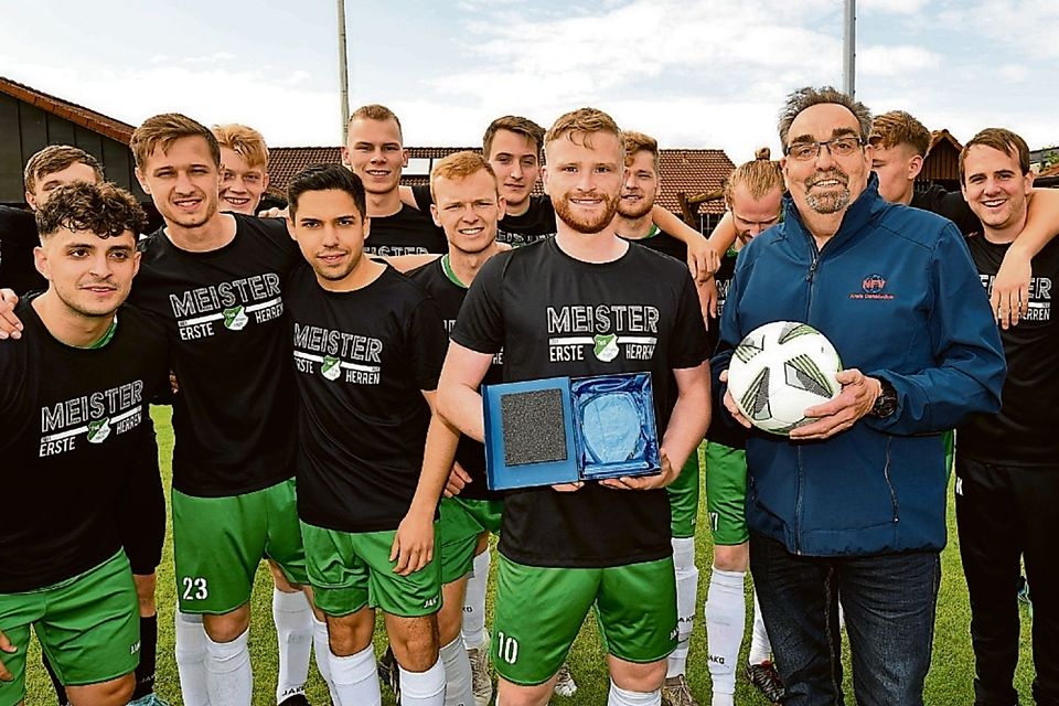 Staffelleiter Ulrich Stenzel (mit Ball) überreichte die Trophäe an TuS-Kapitän Lukas Prätorius.