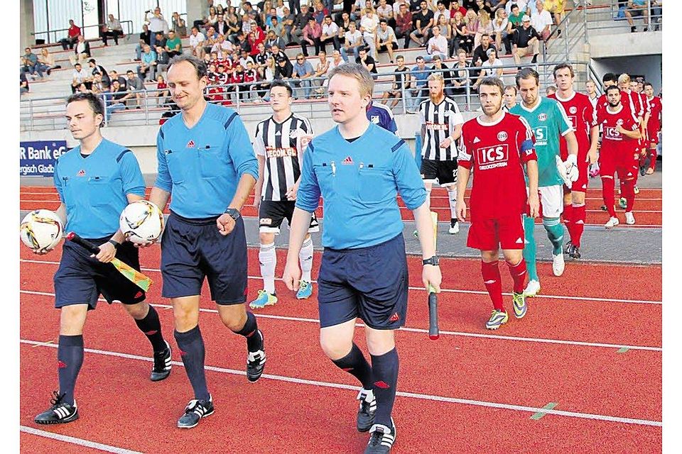 Schiedsrichter Waldemar Ebel (M.) führt die Mannschaften in die gut gefüllte Belkaw-Arena., Foto: Randow