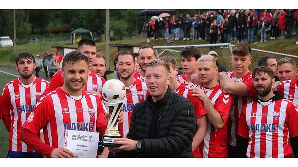 Tim Blöcher, Gebietsverkaufsleiter des Pokalrundensponsors Krombacher, überreicht den „Pokal zum Behalten“ und den obligatorischen Gutschein an Paul Jonas Pfeifer, Kapitän der SG Seelbach/Scheld. Foto: Sven Jessen © Sven Jessen
