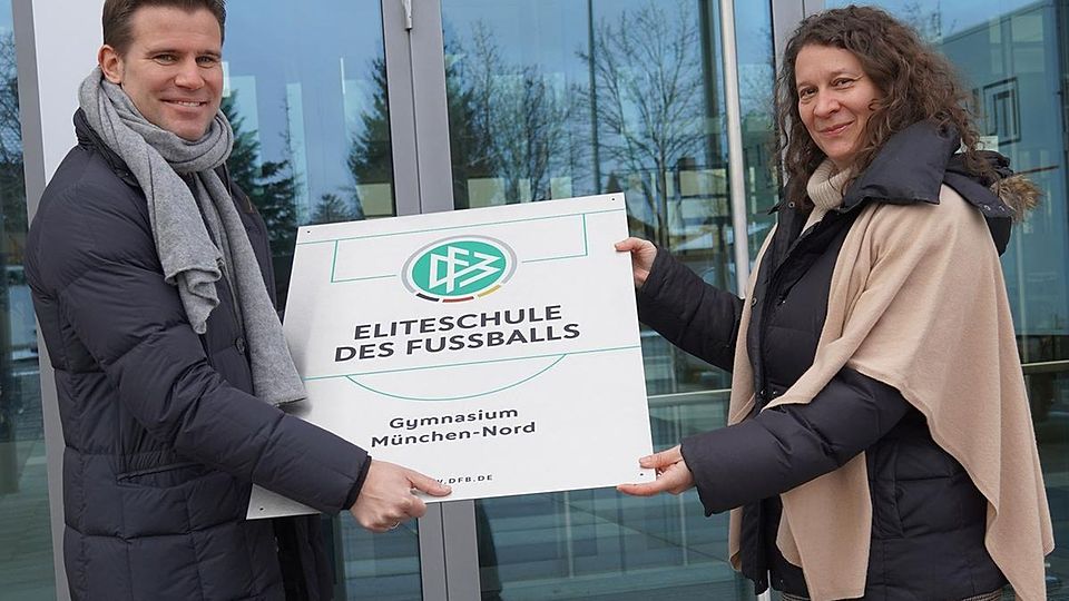 Felix Brych übergibt Schulleiterin Dr. Petra Reinold feierlich die Plakette: Das Gymnasium München-Nord darf sich „Eliteschule des Fußballs“ nennen.