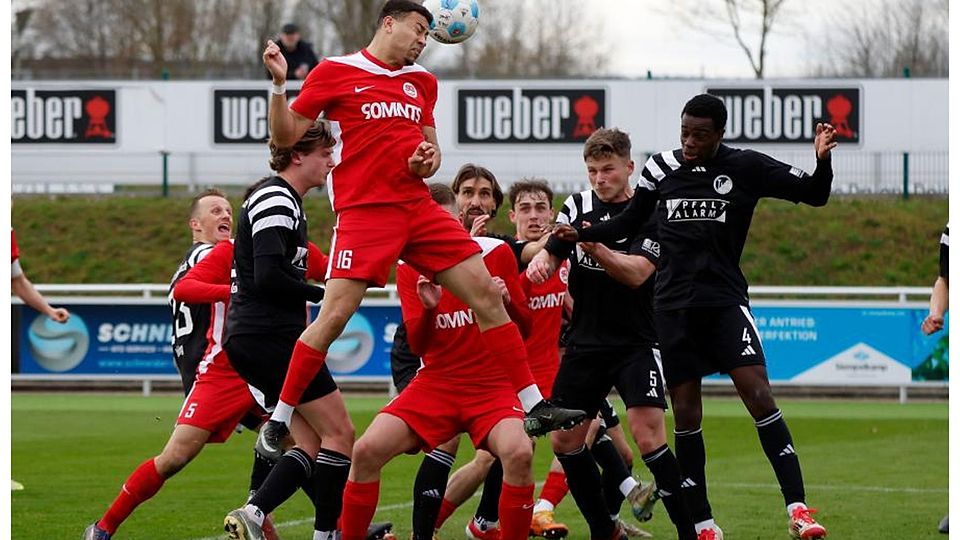 Hüffelsheims Malik Yerima (rotes Trikot) setzt sich im Kopfballduell durch. 	Foto: Edgar Daudistel