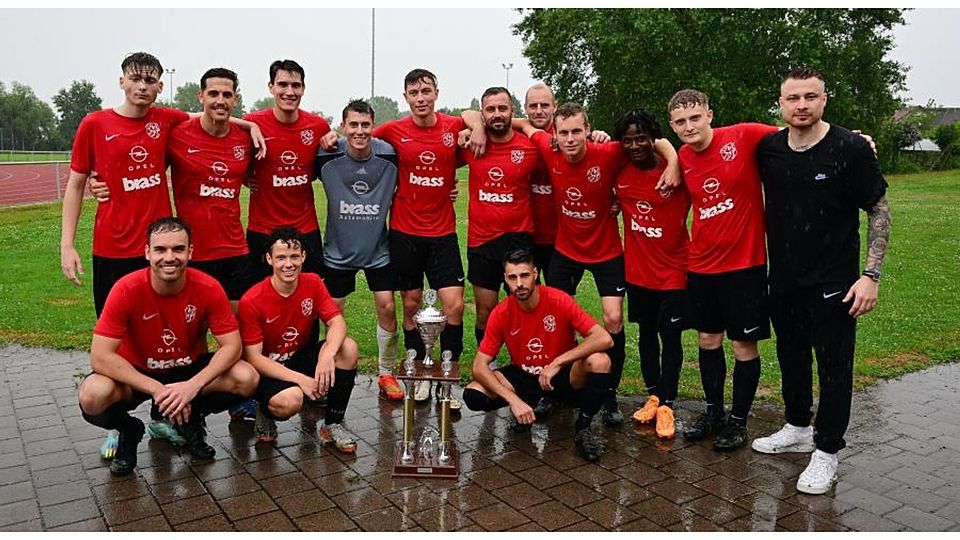 Durchnässte, zufriedene Riedstadtmeister des TSV Wolfskehlen, hinten, von links:  Anel Imamovic, Pascal Maier, Martin Czernecki, Nils Peter, Tim Hammann, Kai Riesle, Pascal Bender (Trainer), Hendrik Brodhecker, Jean-Marc Kla, Etienne Gündel, Marcel Hammann (Trainer). Vorne, von links: Fabian Dietz, Sam Breitwieser, Marcel Pinto-Esteves.	Foto: Uwe Krämer