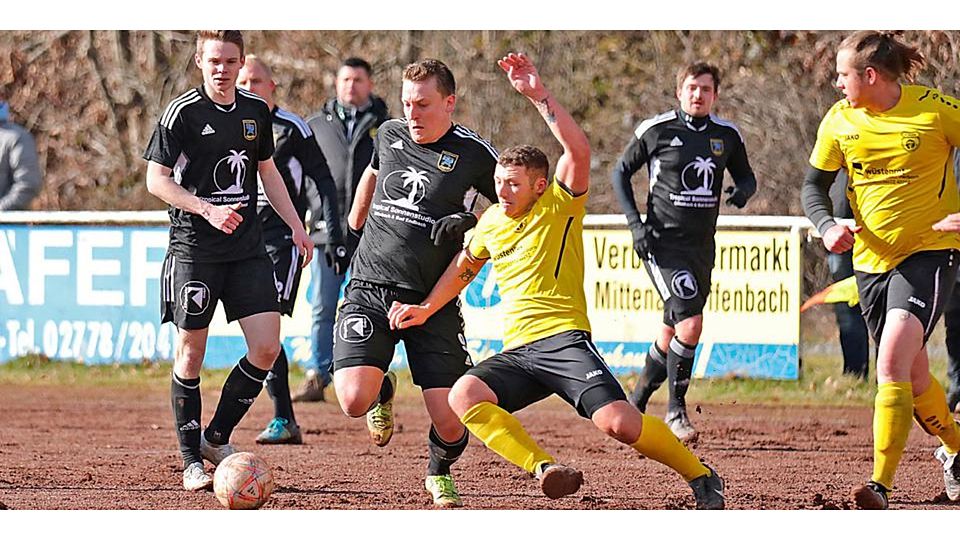  Im Spiel zwischen der SG Aartal und dem FC Merkenbach herrscht Getümmel. In dieser Szene ist der Merkenbacher Jeremy Hermann (vorn im gelbe Trikot) dabei, den Ball vor dem Aartaler Christian Kornrumpf wegzugrätschen. (© Lorenz Pietzsch) 