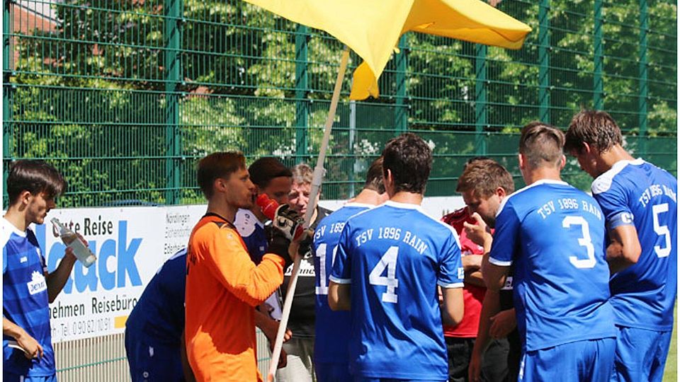 Kevin Maschke, der Torwart des TSV Rain, fungiert hier als Halter des Sonnenschirms, um seine Mannschaftskameraden und Trainer Tobias Luderschmid zu schützen.	F.: Klaus Jais