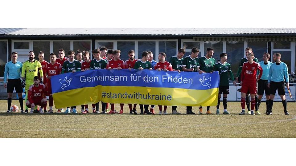 Gegen den Krieg: Die Spieler von Alemannia Waldalgesheim und den Sportfreunden Eisbachtal sowie das Schiedsrichtergespann bekunden mit einem Banner ihre Solidarität mit der Ukraine.
