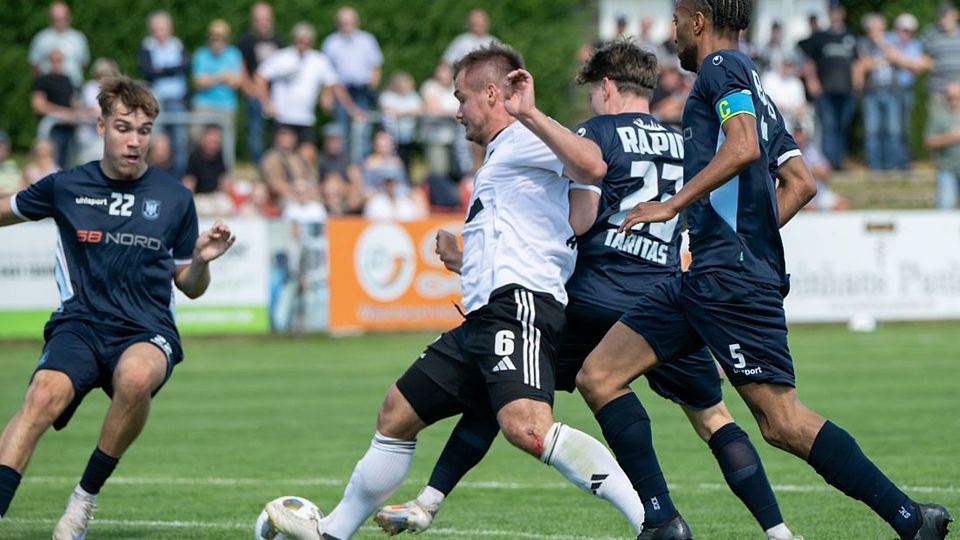Fabian Arndt (Heider SV) wird von Lasse Meier (li), Ivan Taritas und Emmanuel Rivera (Rapid Lübeck) in die Zange genommen.