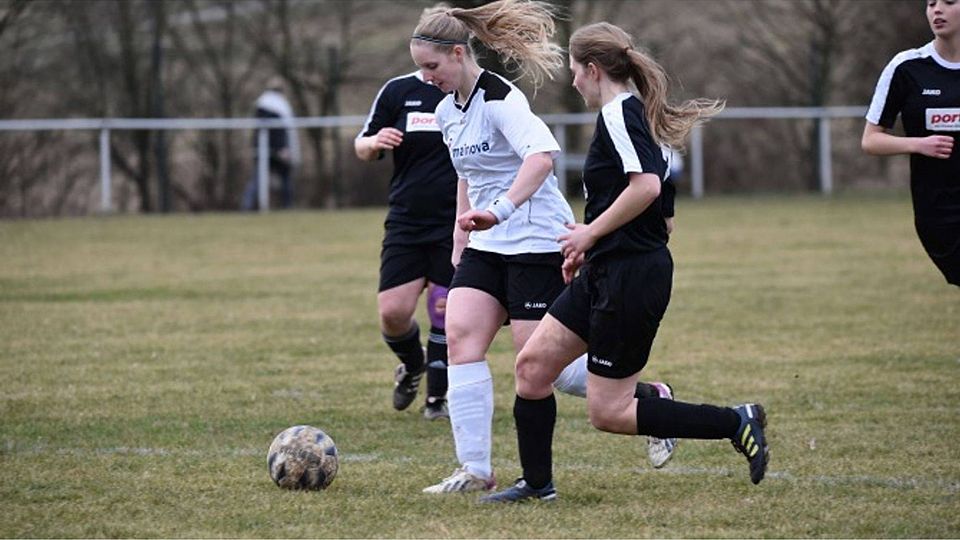 Sina Rau im weißen Trikot der SG Oberau/Düdelsheim II lässt sich von Merle Meyer Wehmann (Mittelbuchen II) nicht vom Ball trennen.