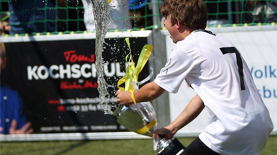 Überschwängliche Wasserdusche mit dem Bananenflankenliga-Pokal: Ein Meisterspieler feiert.  Fotos: Brüssel (2)